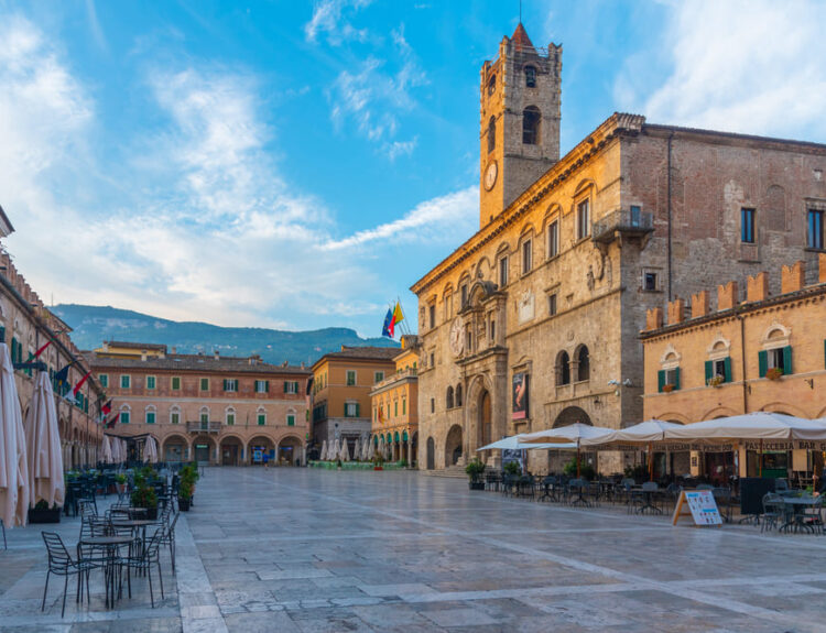 Piazza del Popolo ad Ascoli Piceno al tramonto, meta ideale per un week end in città in Italia, con edifici storici in travertino e caffè all'aperto